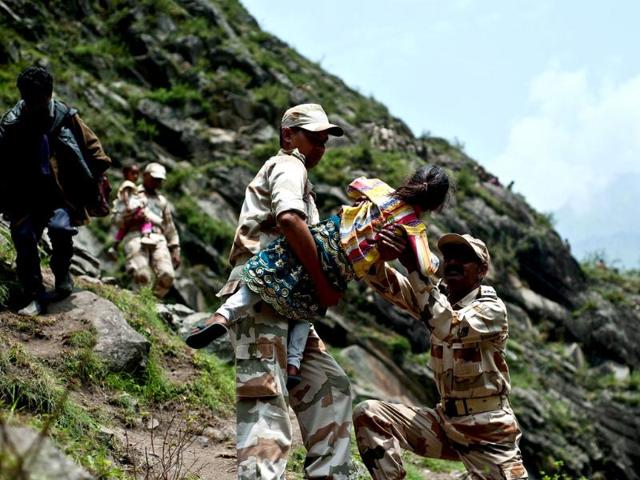 Indo-Tibetan Border Police personnel carry a child as they provide rescue assistance for stranded Indian pilgrims after a section of road was washed away in Govind Ghat. AFP PHOTO