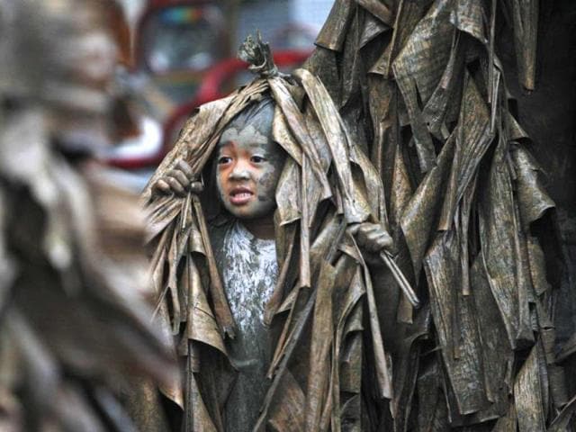 A boy, covered with mud and dried banana leaves, walks around the village to ask for candles before attending a mass celebrating the feast day of the Catholic patron Saint John the Baptist in the village of Bibiclat, Nueva Ecija, north of Manila. (Reuters)