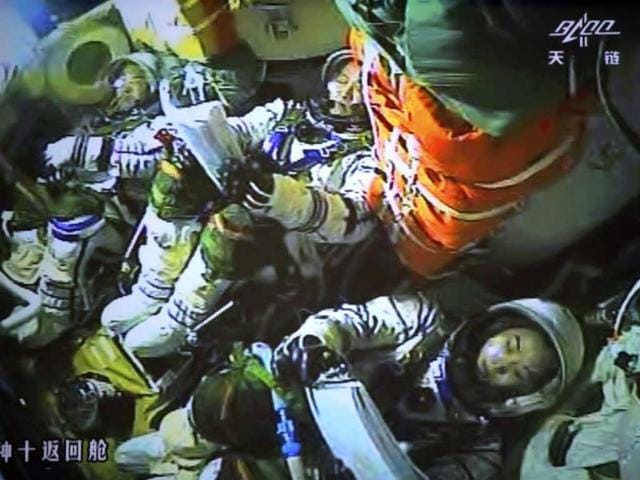 In this photo released by China's Xinhua News Agency, the screen at the Beijing Aerospace Control Center in Beijing shows three astronauts having prepared for the return of the Shenzhou 10 spacecraft to Earth. The space capsule with three astronauts has safely landed on grasslands in northern China after a 15-day trip to the country's prototype space station. (AP)