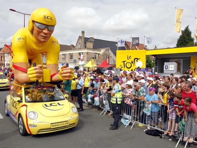 A Le Credit Lyonnais (LCL) vehicle from the publicity caravan of the Tour de France travels past spectators at the start of the third stage of the 99th Tour de France cycling race between Orchies and Boulogne-sur-Mer. (Reuters)
