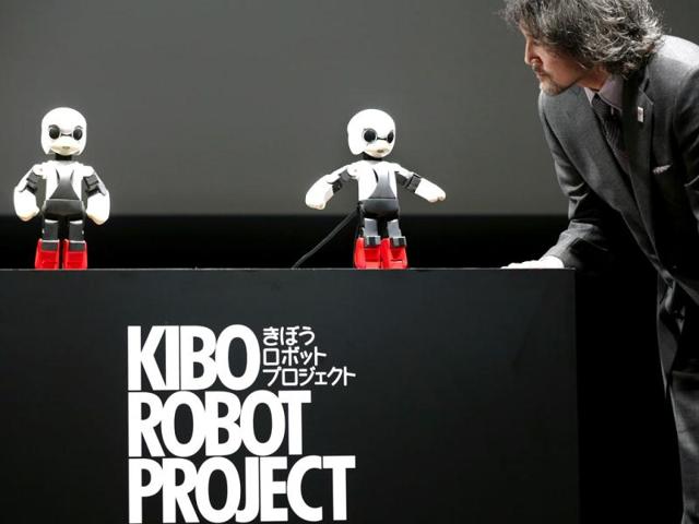 Humanoid communication robot Kirobo, center, talks with Fuminori Kataoka, project general manager from Toyota Motor Corp., during a press unveiling in Tokyo. (AP Photo)