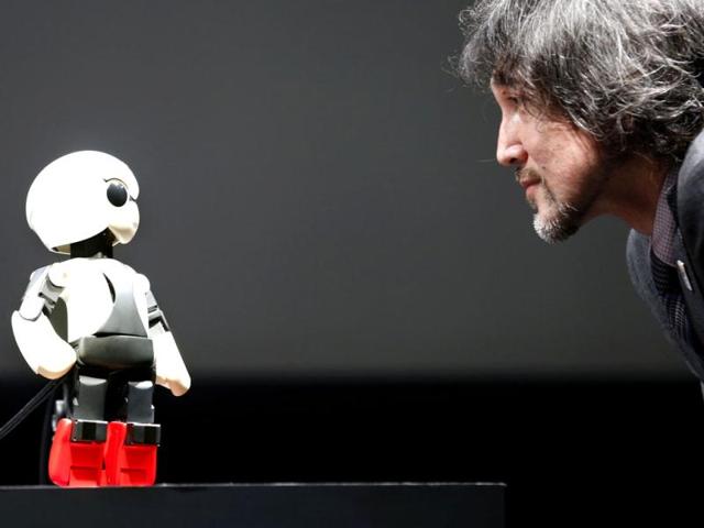 Humanoid communication robot Kirobo, left, talks with Fuminori Kataoka, project general manager from Toyota Motor Corp., during a press unveiling in Tokyo. (AP Photo)