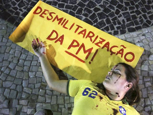 A demonstrator, with fake blood dripped onto herself, lies on the ground during a protest against Brazilian military police at the Copacabana beach in Rio de Janeiro. Reuters