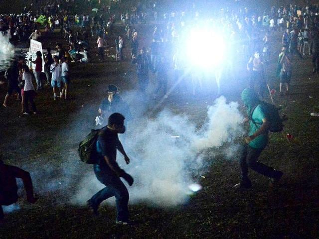 Demonstrators try to kick back a tear gas cannister during a protest in front of the National Congress against government waste and corruption, and the use of public funds to organize international football tournaments in Brasilia. AFP