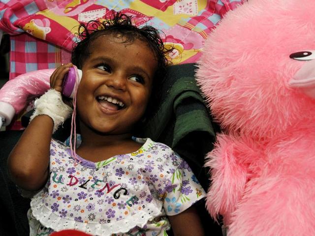 The persistently wailing baby girl who was separated from her parents and rescued after flood disaster in Uttarakhand finally smiled with hope to hear the voice of her father Doon hospital in Dehradun, India. (HT Photo/Rishi Ballabh)