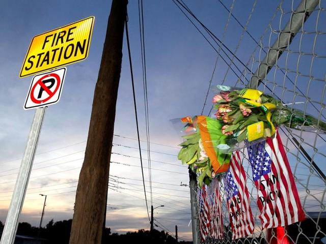 Flowers and American flags are hung outside Station 7 in Prescott, Arizona as tribute to 19 firefighters based out of Station 7 died battling a fast-moving wildfire near Yarnell. (AFP Photo)
