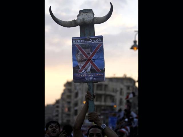 A protester opposing Egyptian President Mohamed Morsi holds a defaced poster of Morsi during a protest in front of El-Thadiya presidential palace in Cairo. (Reuters)