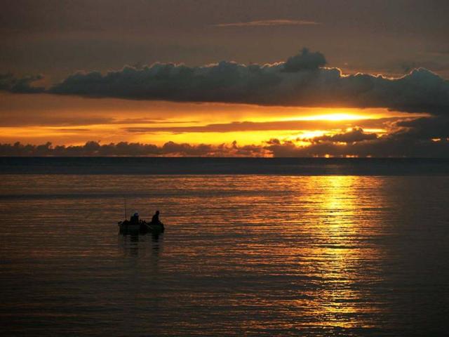 Fishermen sit in their boat as the sun sets in Havana. (Reuters)