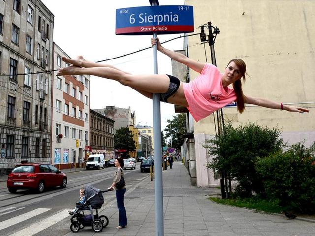 A member of the Avocadoo club performs a pole dance on a street sign pole in Lodz, central Poland. (AFP)