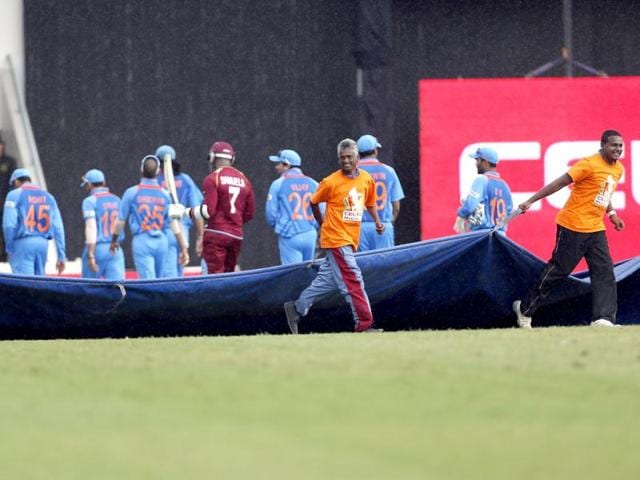 Grounds keepers pull the tarpaulin to cover the pitch as players walk back to the pavilion during a rain delay in the Tri-nation series match between India and the West Indies in Port-of-Spain, Trinidad. (AP)