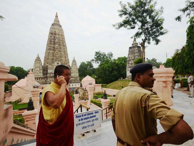 A policeman stands by as a man speaks on the phone at the Bodh Gaya Buddhist temple complex after 9 low-intensity blasts took place injuring two people. AFP