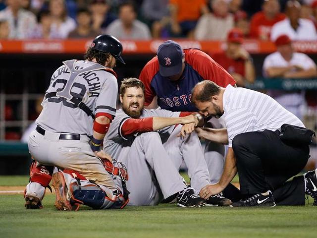 Boston Red Sox pitcher Andrew Miller is checked on by catcher Jarrod Saltalamacchia (L), manager John Farrell (top C) and a trainer after sustaining an injury against the Los Angeles Angels during the seventh inning of an MLB American League baseball game in Anaheim, California. Reuters