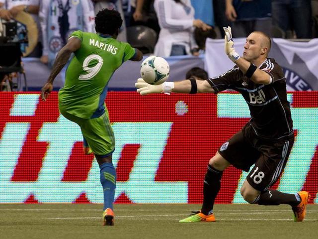 Seattle Sounders' Obafemi Martins, left, of Nigeria, is stopped by Vancouver Whitecaps' goalkeeper Brad Knighton during the first half of an MLS soccer match in Vancouver, British Columbia. AP/The Canadian Press