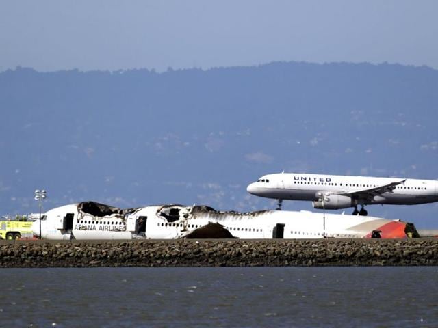 A United Airlines plane lands next to the wreckage of Asiana Flight 214 at the San Francisco International Airport in San Francisco. (AP)