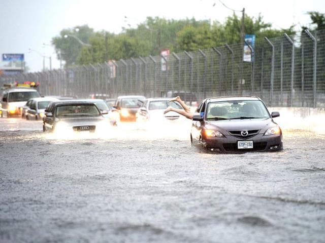 A woman gets back in her car in flood water on Lakeshore West during a storm in Toronto. (AP Photo)