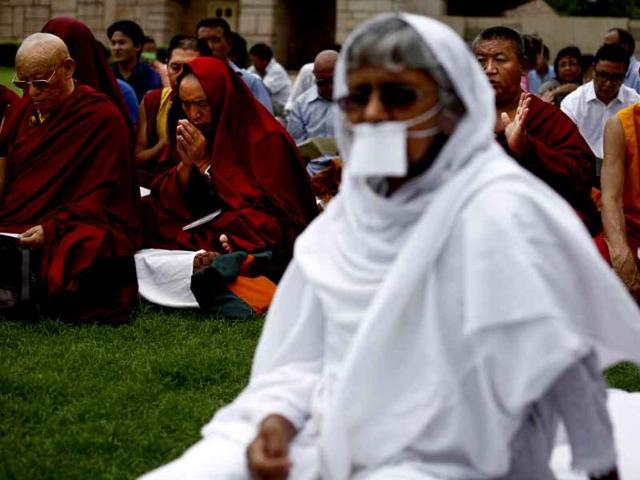 A priest from Jain community joins Tibetan Buddhist monks as they pray for peace following series of blasts in Bodh Gaya on Sunday at Rajghat. (PTI Photo)