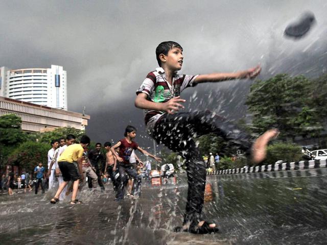 Children, breaking the cliche, instead of surrendering to the idiot box, had fun in the streets as heavy rains lashed Delhi. (HT Photo/Vipin Kumar)