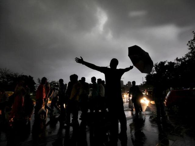 With his arms wide open, one hand holding an umbrella, a Delhiite cautiously welcomes the rain. (HT Photo/Raj K Raj)