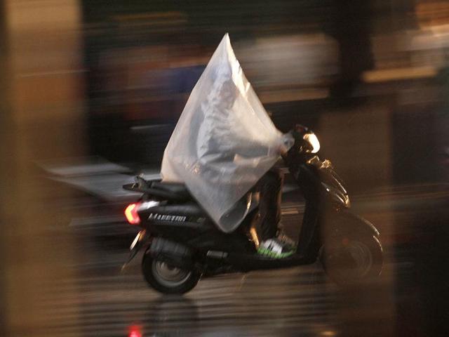 Trying to escape the rain God's fury, a man covers himself in plastic sheet as he makes his way in the rain. (HT Photo/Virendra Singh Gosain)