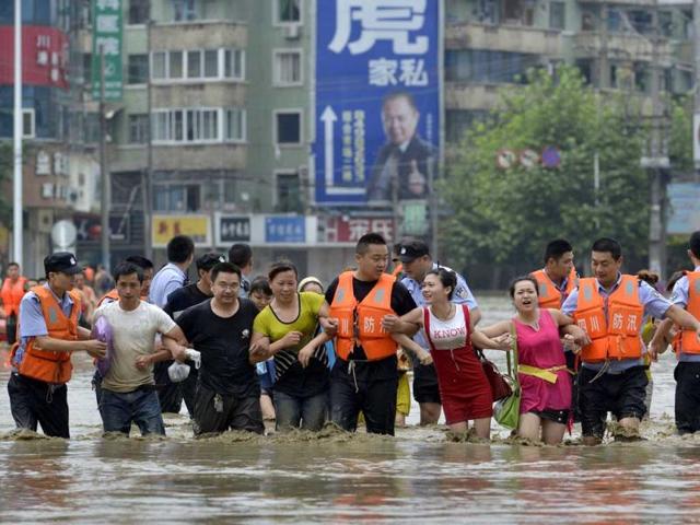 Policemen hold the arms of residents as they walk on a flooded street after heavy rainfall hit Chengdu, Sichuan province. Reuters