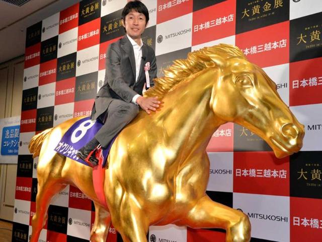 Japanese leading jockey Yutaka Take poses on a life-sized statue of the Japanese legendary Oguri Cap horse displayed at the opening of the Gold Expo event at Tokyo's Mitsukoshi department store. AFP