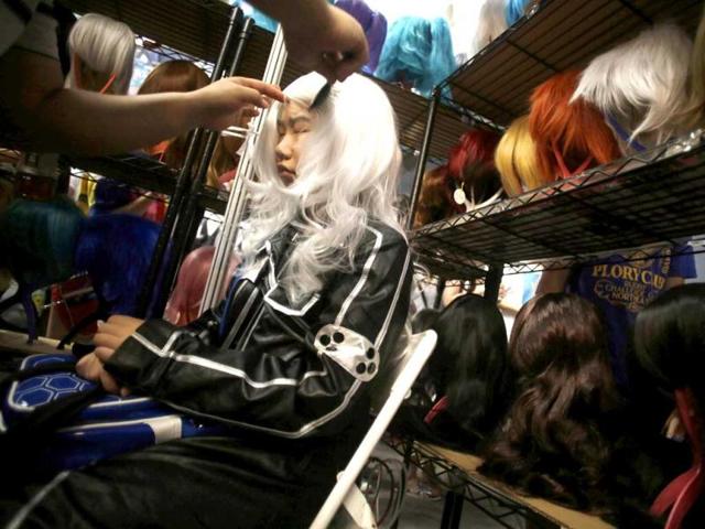 A costumed visitor is helped to wear a wig at a wig shop during the China International Comics and Games Expo in Shanghai, China. AP Photo