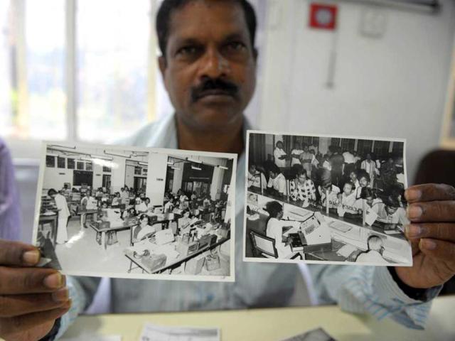 Telecom supervisor, RG Vijay Kumar, shows the photographs taken in 1980 of old system of working telegrams at telegraph office in Hyderabad. (AFP Photo)