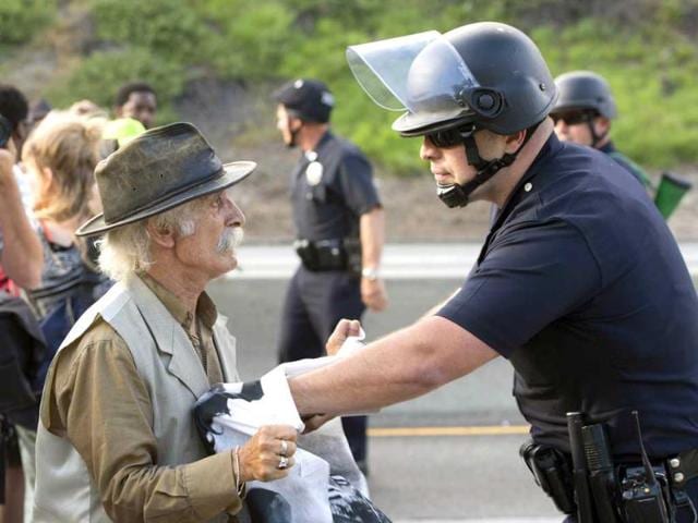 Police officers push back a protestor on the 10 Freeway after demonstrators angry at the acquittal of George Zimmerman walk onto the freeway, stopping highway traffic, in Los Angeles. (AFP Photo)