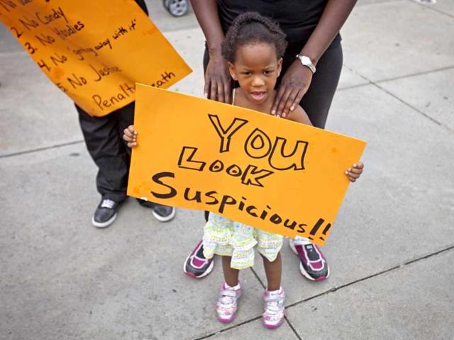 Jediah Jones, 3, holds a sign as her mother, stands behind her during a protest the day after George Zimmerman was found not guilty in the 2012 shooting of Trayvon Martin in Atlanta. (AP Photo)
