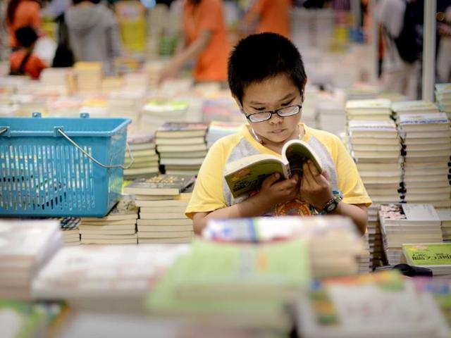 A boy reads a book at the Hong Kong Book Fair. Photo: AFP / Philippe Lopez