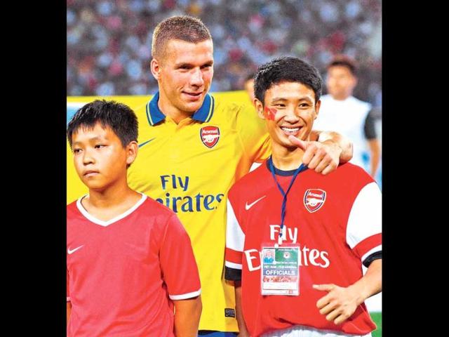Vu Xuan Tien (R) a Vietnamese football fan who is dubbed the "Running Man" after chasing Arsenal's team bus five miles through the streets of Hanoi, poses with Arsenal's Lukas Podolski at Hanoi's My Dinh stadium. (AFP photo)