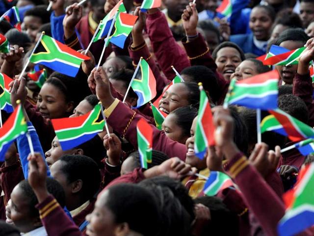 School kids from the Milton Mbekela school wave flags as they sing wishing former South African president Nelson Mandela a happy birthday in Qunu. Nelson Mandela spent his 95th birthday in hospital but his health was steadily improving. AFP photo