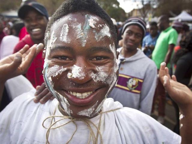 A well-wisher with cake spread on his face smiles after some of a large birthday cake for former South African Nelson Mandela was given out to the crowd gathered in Pretoria, South Africa. AP Photo