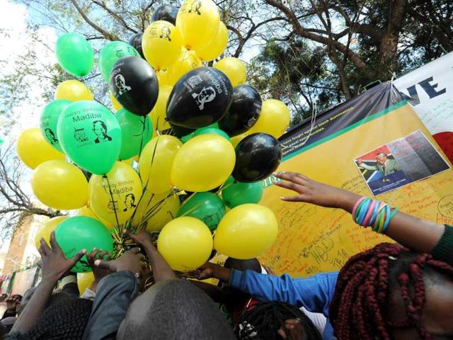 People try to grab a balloon with a portrait of former South African president Nelson Mandela on it on his birthday outside the Medi Clinic Heart Hospital in Pretoria. AFP photo
