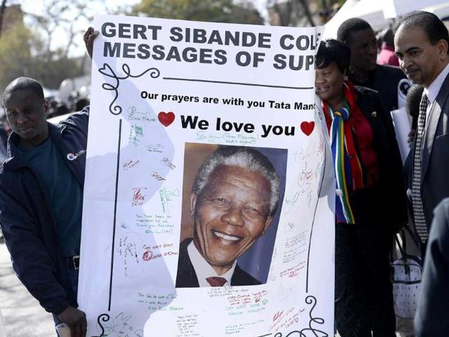 People hold on a poster bearing a portrait of former South African president Nelson Mandela to wish him a happy birthday outside the Medi Clinic Heart Hospital in Pretoria. AFP photo