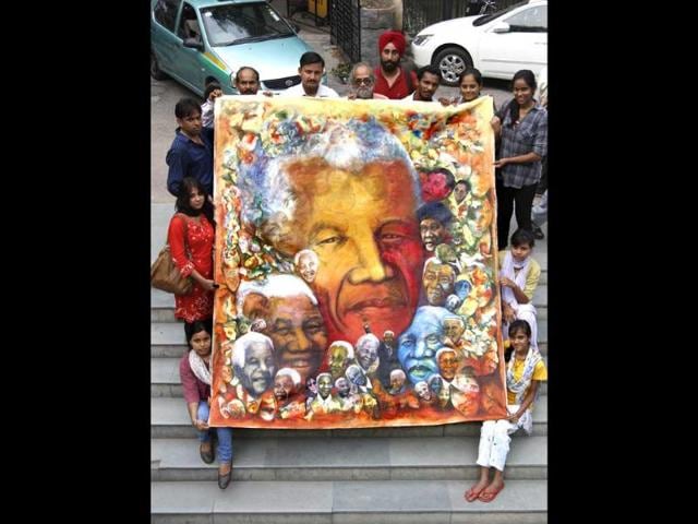 Artists of health education & environment awareness society pose with the painting of former South African president Nelson Mandela in New Delhi on his birthday. HT Photo/Virendra Singh Gosain
