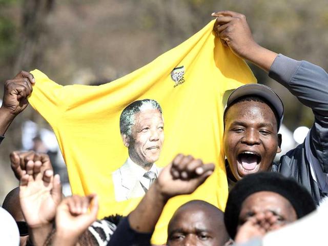 People hold on a shirt bearing a portrait of former South African president Nelson Mandela to wish him a happy birthday outside the Medi Clinic Heart Hospital in Pretoria. AFP photo