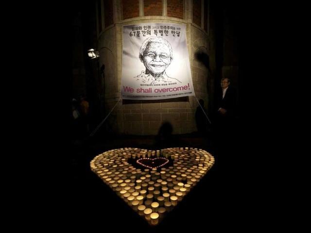 A South Korean man stands near the banner of former South African president Nelson Mandela during a meeting to celebrate for Nelson Mandela's 95th birthday in Seoul, South Korea. AP Photo