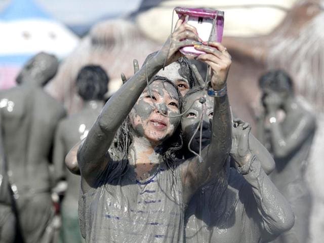 Tourists take pictures with a mobile phone after playing in the mud during the Boryeong Mud Festival at Daecheon beach in Boryeong, southwest of Seoul. Reuters