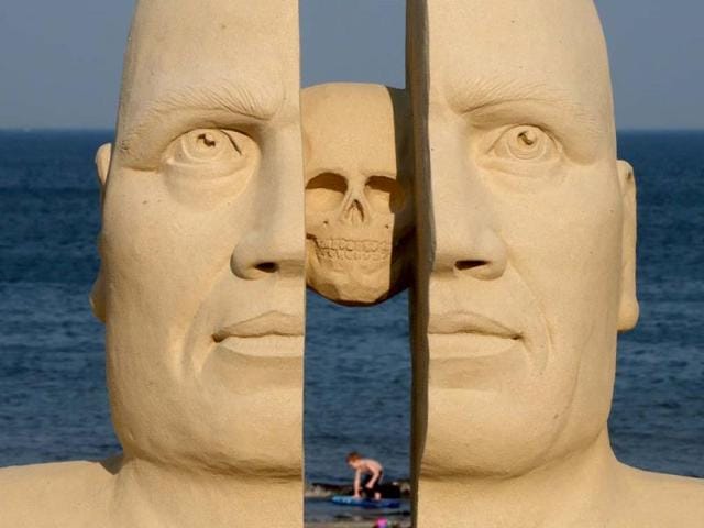 A boy plays in the waters of Massachusetts Bay framed by a large sand sculpture at Revere Beach in Revere, Massachusetts. (AP Photo)