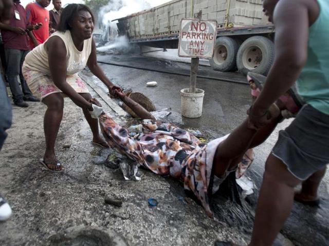 Relatives remove the body of rice vendor Dasilia Daniel, who was accidentally shot dead during a road rage incident as she walked to work in the Petionville suburb of Port-au-Prince, Haiti. (AP Photo)