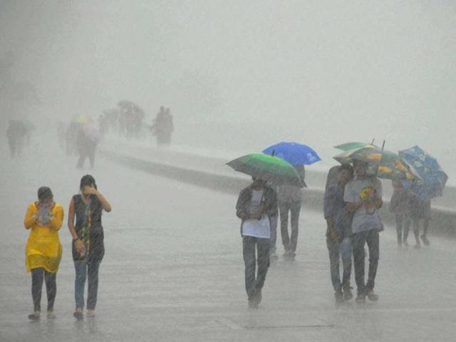 People walk in heavy rains at Marine Drive in Mumbai on Tuesday. (PTI Photo)