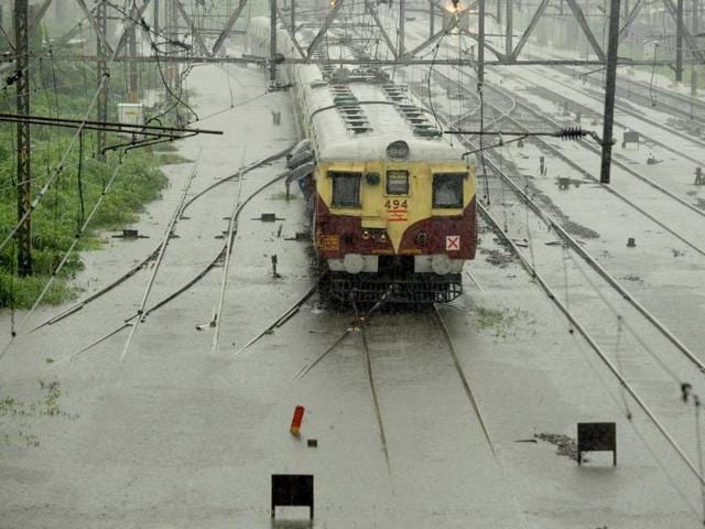 A local train passes over flooded railway tracks during rain showers in Mumbai. (AFP Photo)