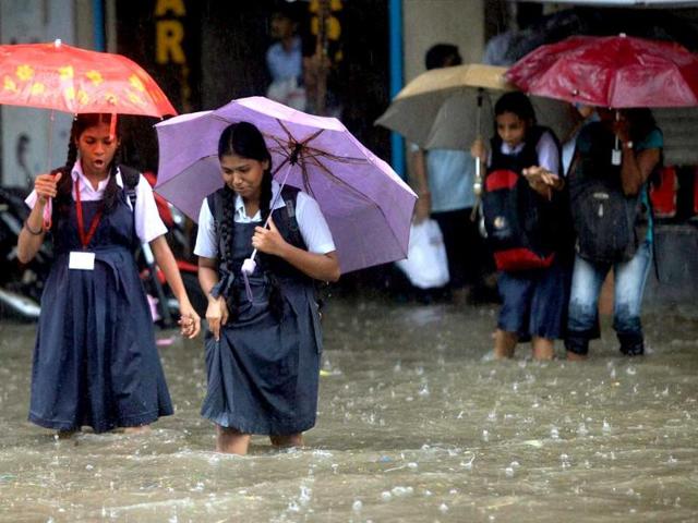 Schoolgirls wade through a flooded street during showers in Mumbai on Tuesday. (PTI Photo)
