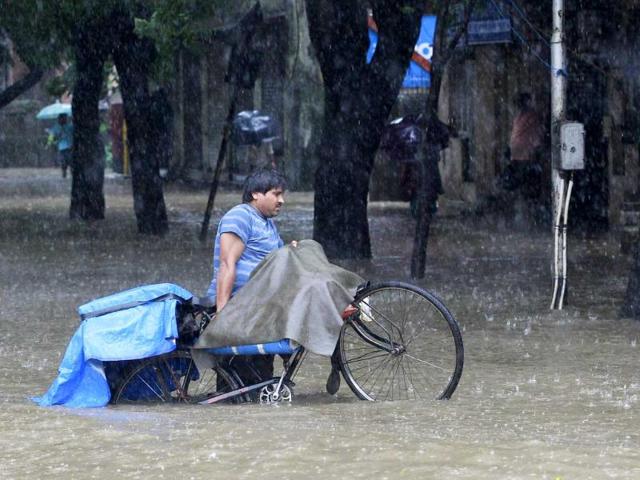 A man carries his bicycle through flooded streets during heavy rain in Mumbai, India. (AP Photo)