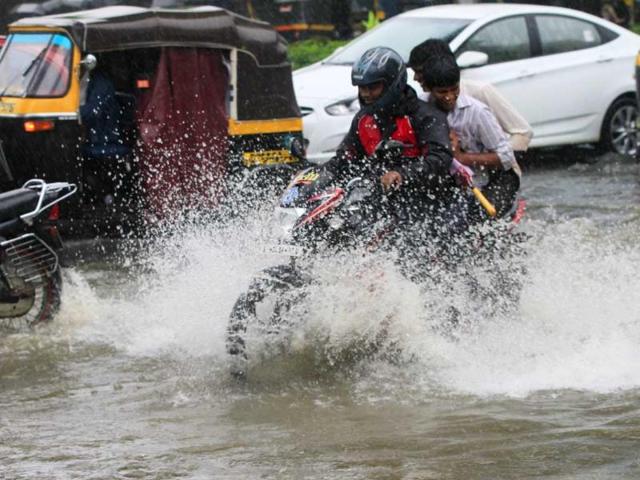 People drive through a flooded street during rain showers at Andheri subway in Mumbai, India. (HT Photo)
