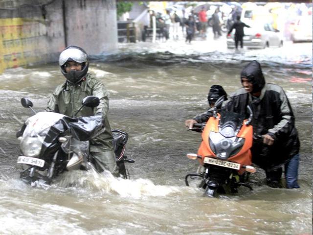 People drive through a flooded street during heavy rains in Mumbai. (Satish Bate/HT)
