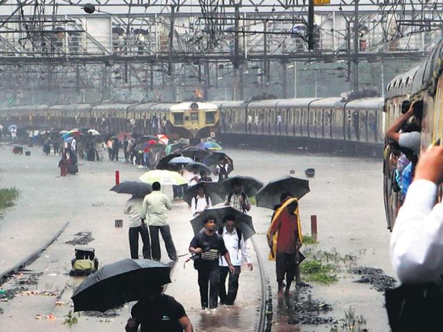 Commuters walk on tracks that were flooded between Kurla and Sion stations. Train services in Mumbai were hit on Tuesday owing to the heavy rain. (HT/Santosh Harhare)