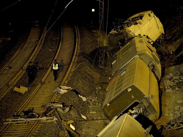 Spanish police officers walk next to derailed cars at the site of a train accident near the city of Santiago de Compostela. A train hurtled off the tracks in northwestern Spain. The train, carrying at least 200 passengers, had left Madrid and was heading for the northwestern town of Ferrol as the Galicia region was preparing celebrations in honour of its patron saint James. AFP PHOTO