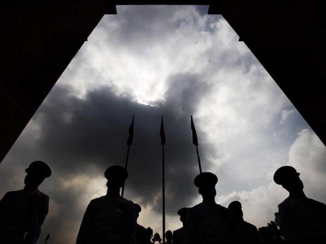 Indian navy personnel are silhouetted as they pay tribute at India Gate war memorial on the 14th anniversary of India's victory in the Kargil War in New Delhi. (AP Photo)
